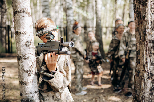 Boy looking into the optical sight a weapon. Children playing laser tag shooting game in outdoor. War simulation game photo