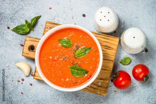 Fotografie Tomato soup with basil. Top view at white background.