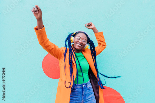 Italy, Milan, Stylish woman with headphones dancing against wall photo