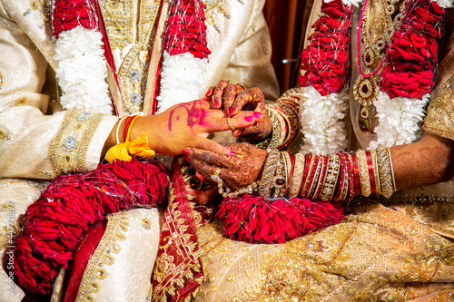hands of Indian couple passing ring in finger.