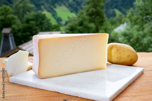 Tastes of Savoia, French cow cheese for gratin abondance, potatoes and french mountains village in Haute-Savoie on background photo