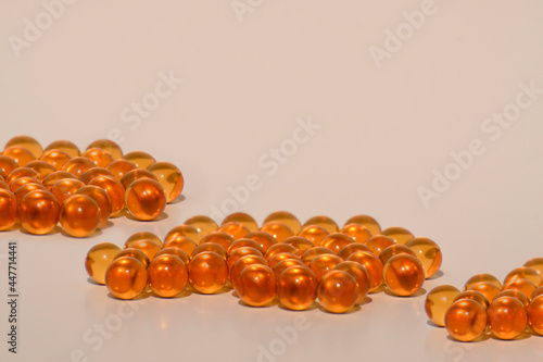 Fish oil capsules. Bright orange transparent capsules on a white background. Close-up. 