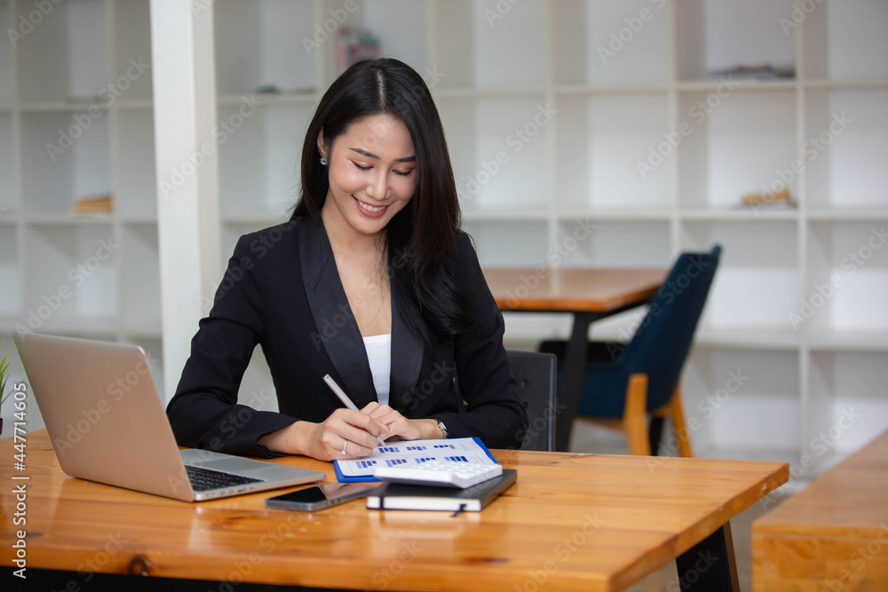 Portrait Beautiful Asian woman working happily and success in work and profit in business made by using PC Laptop Smart phone and business analysis chart Portrait Beautiful Asian woman working happily and success in work and profit in business made by using PC Laptop Smart phone and business analysis chart