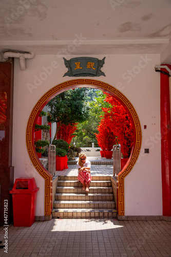 Kuala Lumpur, Malaysia - 09 February 2018: Travel lifestyle view of girl sitting under traditional archway at Chinese Thean Hou Temple in Kuala Lumpur, Malaysia. photo