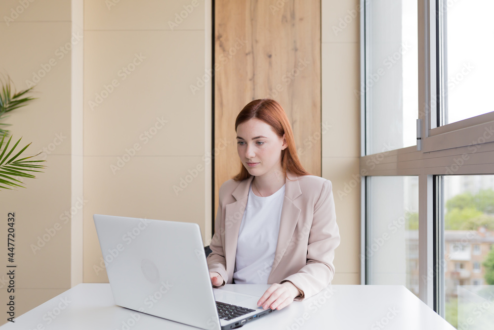 Serious business woman working on laptop sitting at office desk Serious business woman working on laptop sitting at office desk
