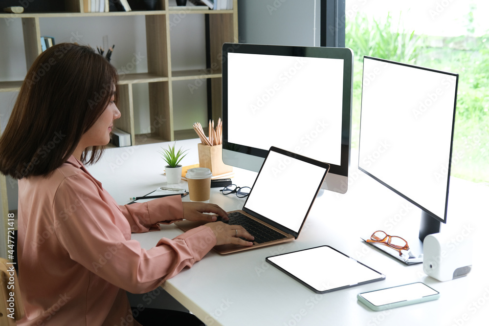 Female programmer working with laptop, two computers and tablet, blank screen of devices, Programmer working concept. Female programmer working with laptop, two computers and tablet, blank screen of devices, Programmer working concept.