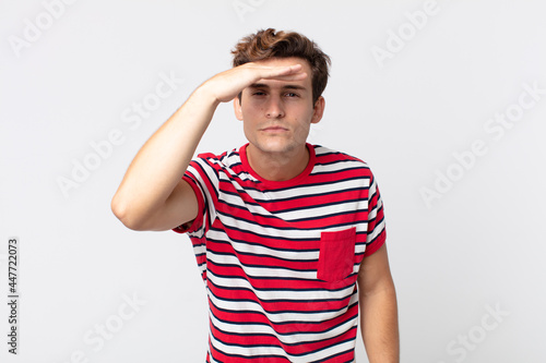 Photography young handsome man looking bewildered and astonished, with hand over forehead lo