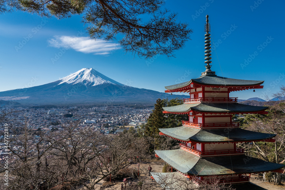 Iconic view of Mt Fuji and Chureito Pagoda. Beautiful red Shinto shrine with mountain background and Fujiyoshida city in Japan.