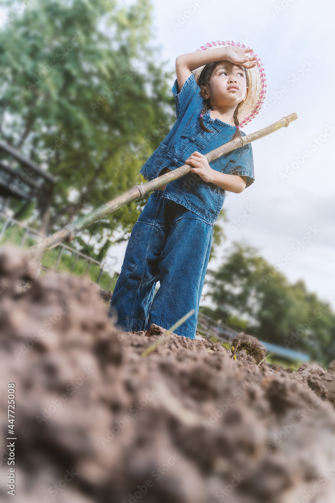 A young farmer girl is enjoying gardening and digging holes.