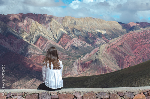 Rear view of a woman sitting on a wall looking at mountain landscape, El Hornacal, Jujuy, Argentina photo