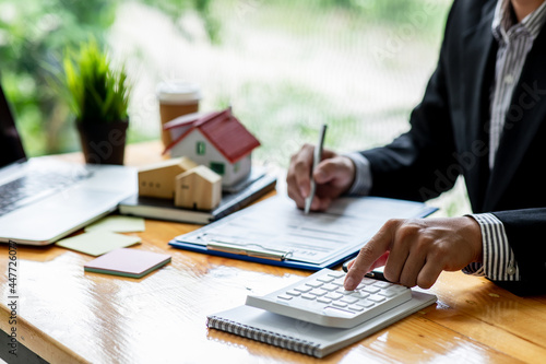 Close up house model with business man signs a purchase contract or mortgage for a home,  buy and sell home  insurance concerning mortgage loan Real estate concept. photo