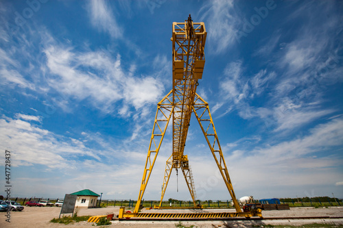 Power yellow gantry crane against scenic blue sky with white clouds. photo