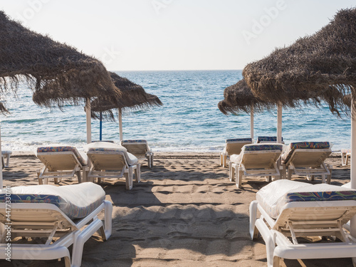 Loungers next to umbrellas prepared for tourists to lie down and enjoy the beach