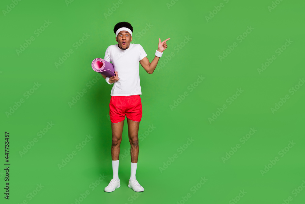 Photo of shocked funny guy direct finger empty space wear t-shirt shorts sneakers isolated green color background Photo of shocked funny guy direct finger empty space wear t-shirt shorts sneakers isolated green color background