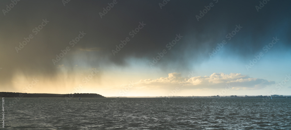 Poole Harbour wind surfers at sunset with grey clouds Poole Harbour wind surfers at sunset with grey clouds