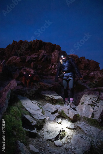 Travel lifestyle view of girl and adventure dog hiking with head torch in dark on Striding Edge near Helvellyn mountain peak in Lake District National Park, England, UK. photo