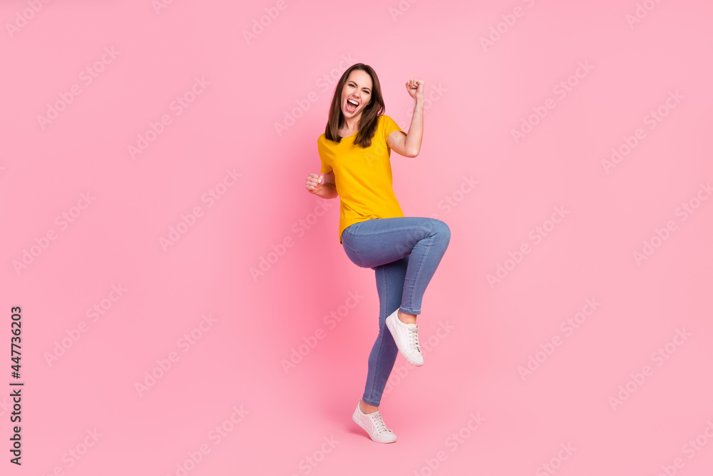 Full body photo of hooray brunette hair young lady hands fists wear yellow t-shirt jeans isolated on pink color background Full body photo of hooray brunette hair young lady hands fists wear yellow t-shirt jeans isolated on pink color background
