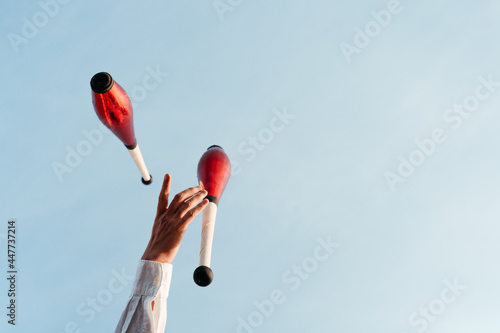 Juggler performing circus trick against blue sky photo