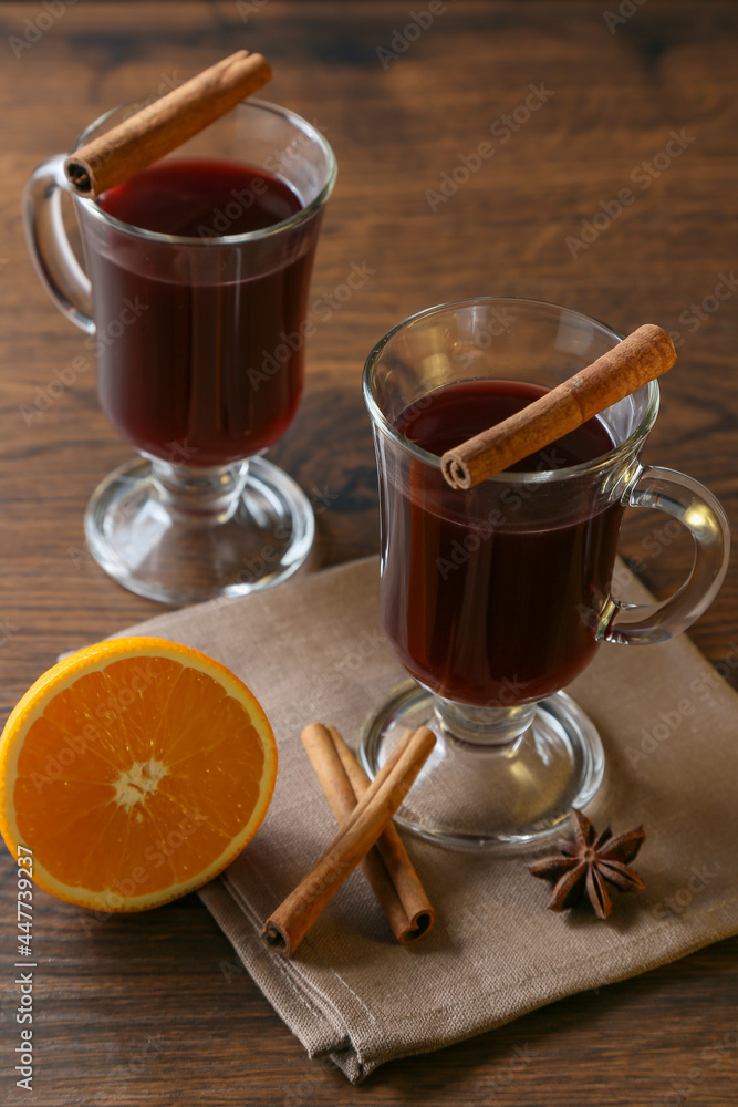 Mulled wine in glass cups with cinnamon and oranges on a wooden table. Mulled wine in glass cups with cinnamon and oranges on a wooden table.