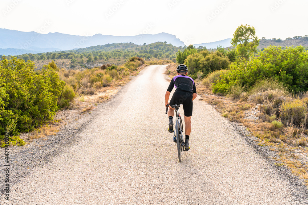 Professional cyclist pedaling on lonely road in the mountain on sunny day Professional cyclist pedaling on lonely road in the mountain on sunny day