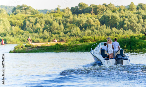 A man, a woman, a child, are floating in a boat with a motor on the river