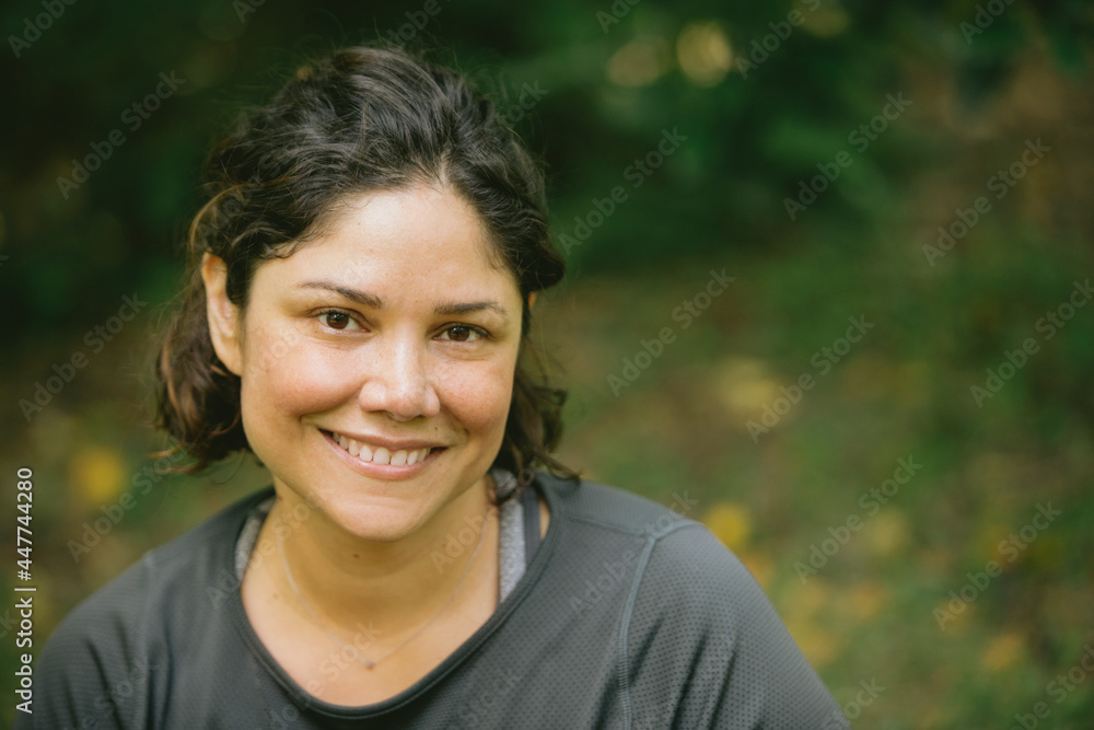 Delighted young ethnic woman relaxing in green park and smiling Delighted young ethnic woman relaxing in green park and smiling