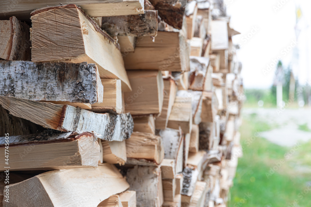 stacked woodpile of birch firewood in nature in the village on a bright summer day. Close-up