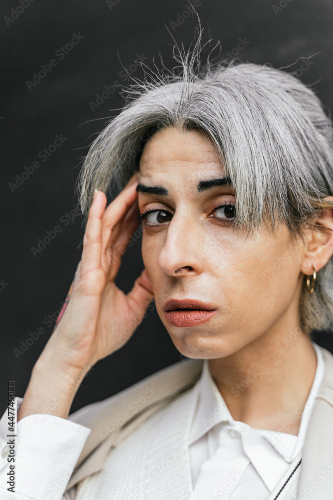 Serious transgender woman with gray hair in street