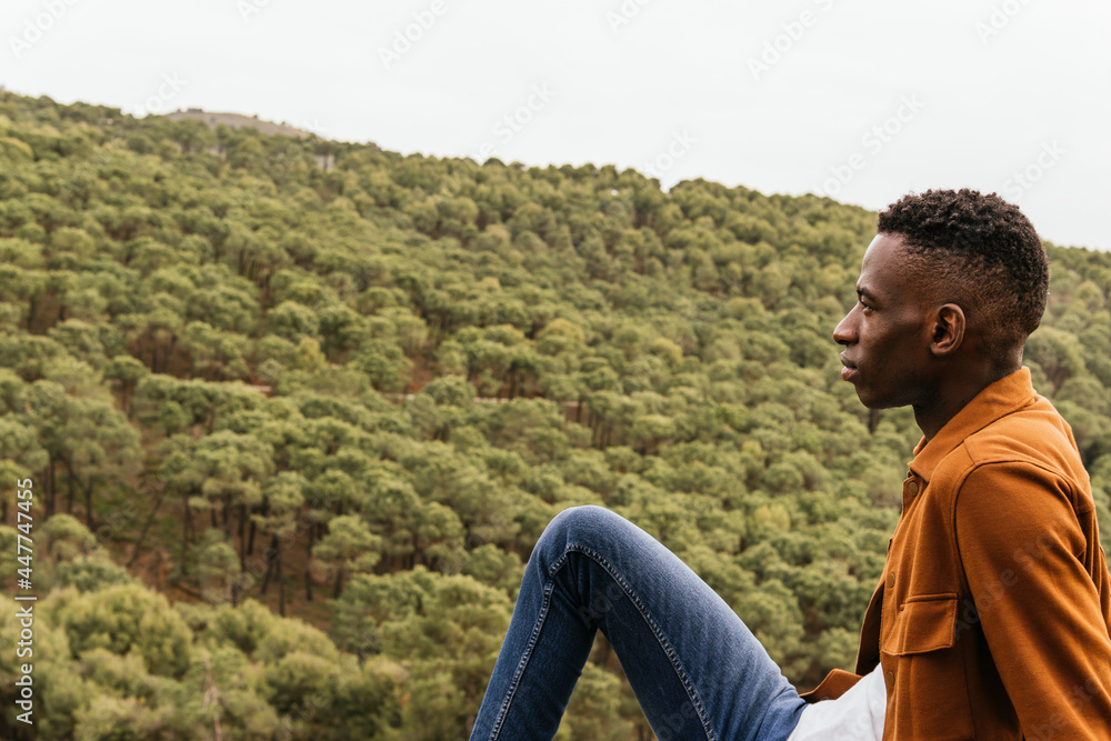 Thoughtful black man in stylish outfit sitting in nature Thoughtful black man in stylish outfit sitting in nature