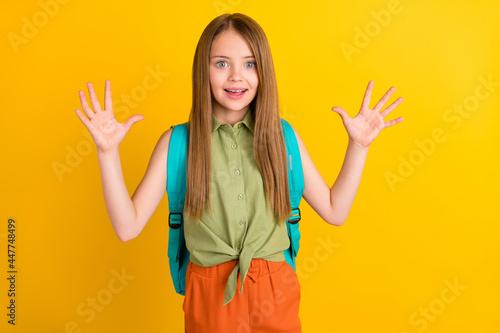 Photo of funky blond small girl hands up wear bag khaki blouse isolated on yellow color background © deagreez