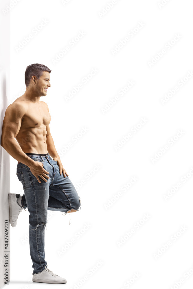 Full length profile shot of a shirtless fit man wearing jeans and leaning on a wall Full length profile shot of a shirtless fit man wearing jeans and leaning on a wall