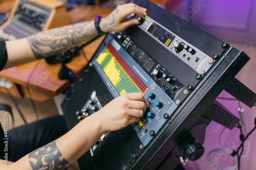 Crop anonymous sound man working with mixing console in music studio