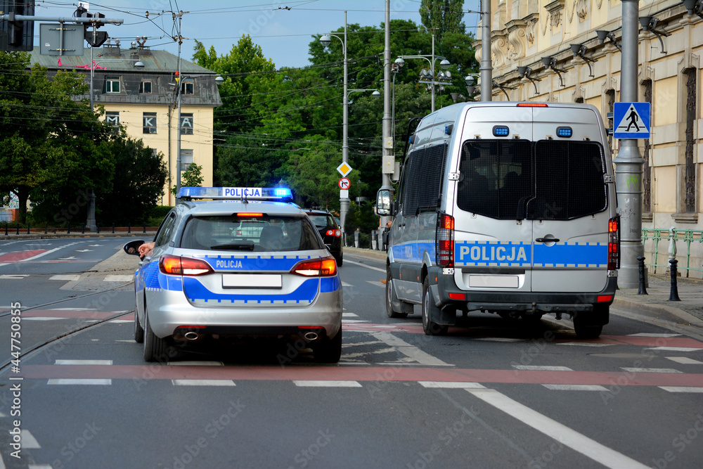 Polska policja drogowa podczas pracy na drodze w mieście. Pojazdy policyjne.  - obrazy, fototapety, plakaty 