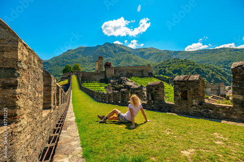 Woman sitting on top of Bellinzona, historic city in Switzerland. Walls of Montebello castle in Bellinzona, capital city of Ticino canton in Switzerland. photo