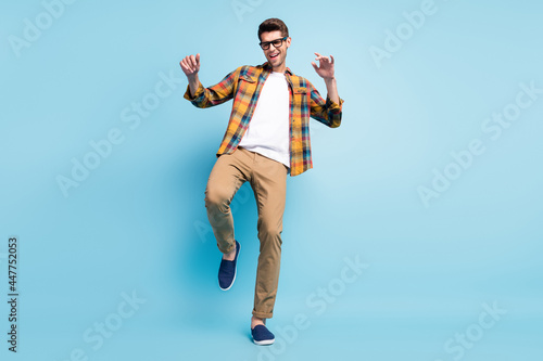 Photo of confident funky young guy dressed plaid shirt smiling dancing isolated blue color background