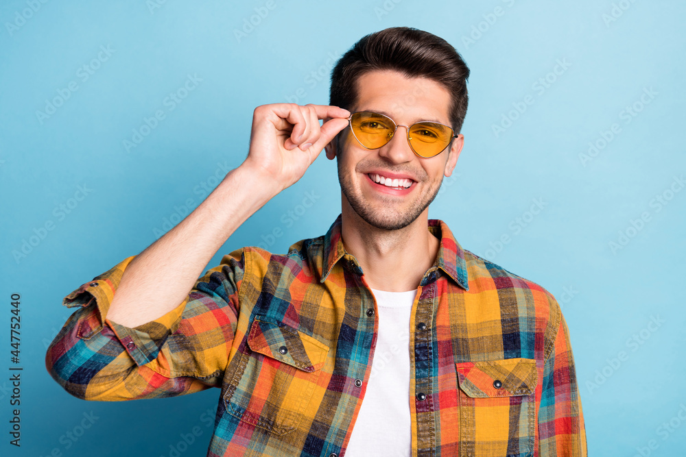 Portrait of attractive toothy cheerful guy touching specs good mood isolated over bright blue color background Portrait of attractive toothy cheerful guy touching specs good mood isolated over bright blue color background