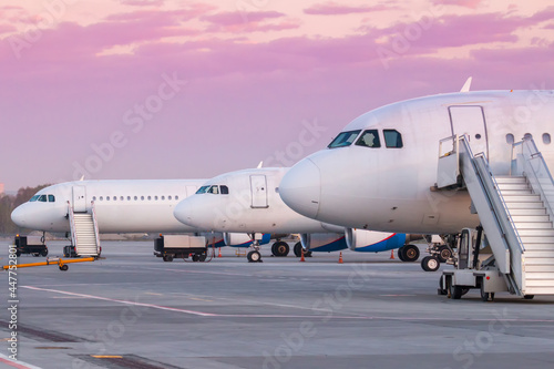 White passenger airplanes noses with a boarding stairs at the morning airport apron