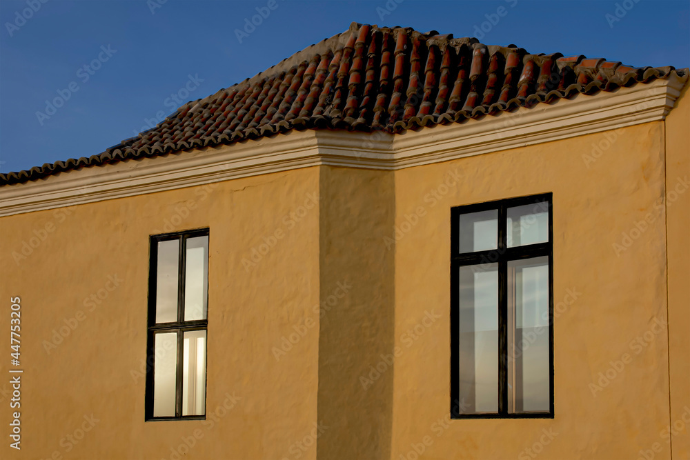 Windows included in an urban setting with yellow textured walls.