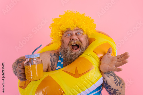 Fat happy man with wig in head is ready to swim with a donut lifesaver