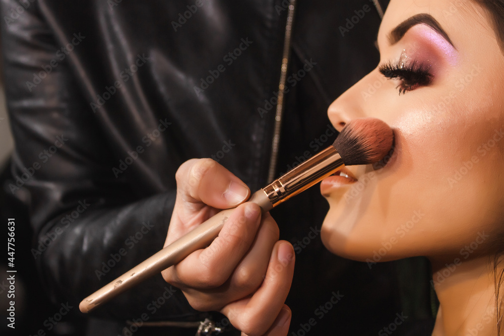 Obraz premium Detail shot of a make-up artist coloring the cheeks of a beautiful young girl in the beauty salon.