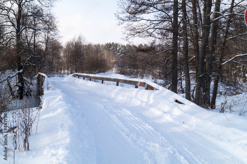 Winter road over a wooden bridge in the forest