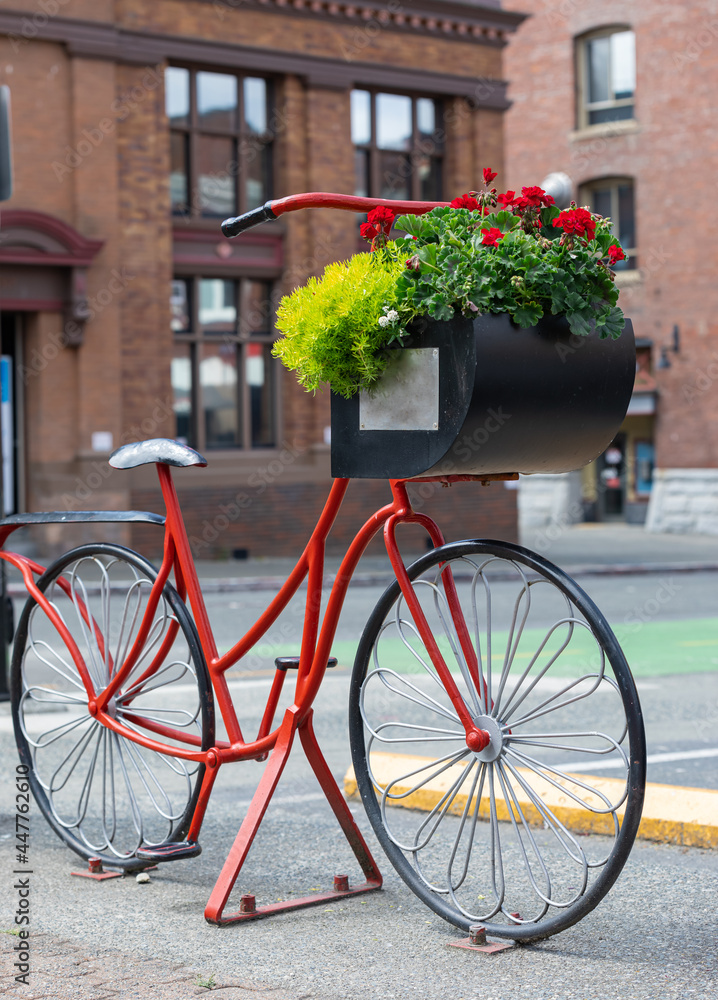 Beautiful red painted bicycle with a bucket of colorful flowers on the street of the city.