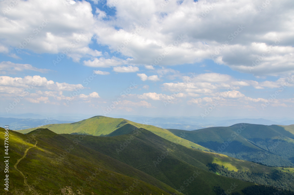 Scenic view of green grassy mountain ridge against blue cloudy sky. Carpathian mountains, Ukraine Scenic view of green grassy mountain ridge against blue cloudy sky. Carpathian mountains, Ukraine