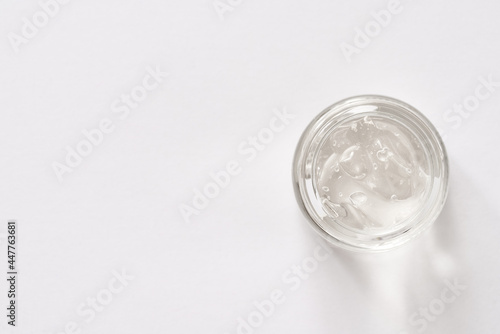 Aloe vera gel in a cosmetic glass jar on white background, top view. Natural skin moisturizer.