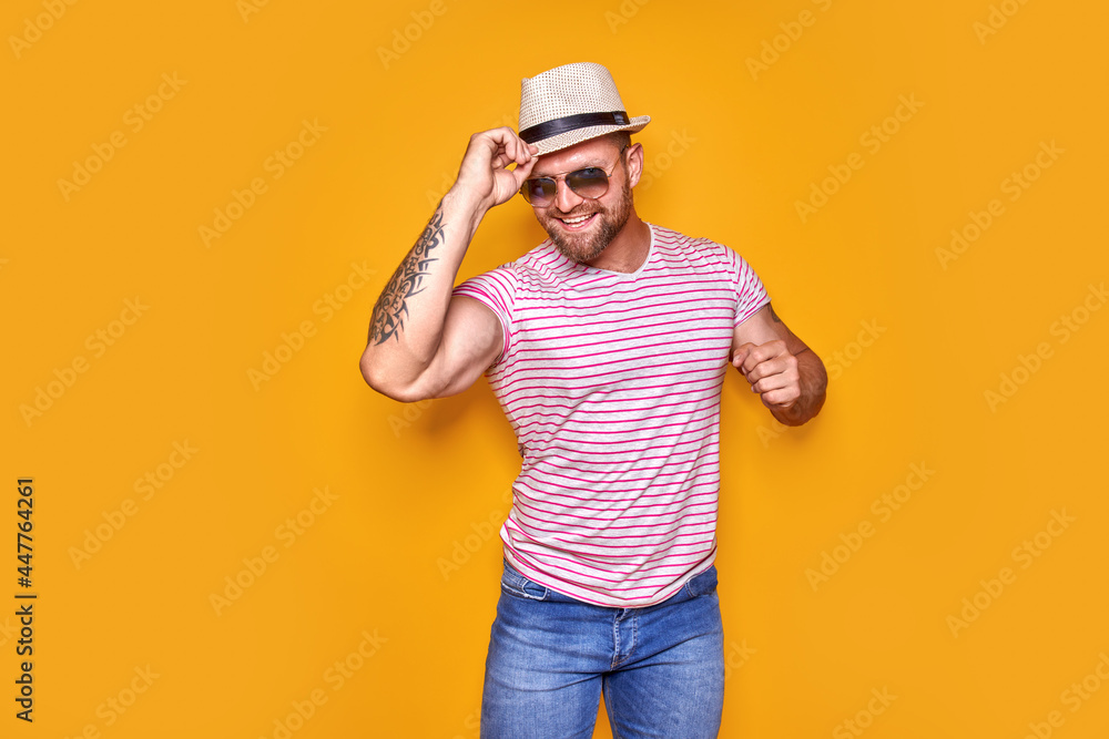 Portrait of optimistic funky guy dance wear summer look straw hat, sunglasses isolated on yellow color background Portrait of optimistic funky guy dance wear summer look straw hat, sunglasses isolated on yellow color background