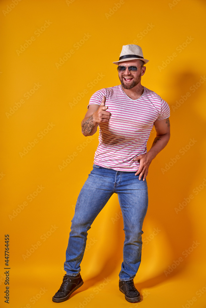 Portrait of optimistic funky guy dance wear summer look straw hat, sunglasses isolated on yellow color background Portrait of optimistic funky guy dance wear summer look straw hat, sunglasses isolated on yellow color background