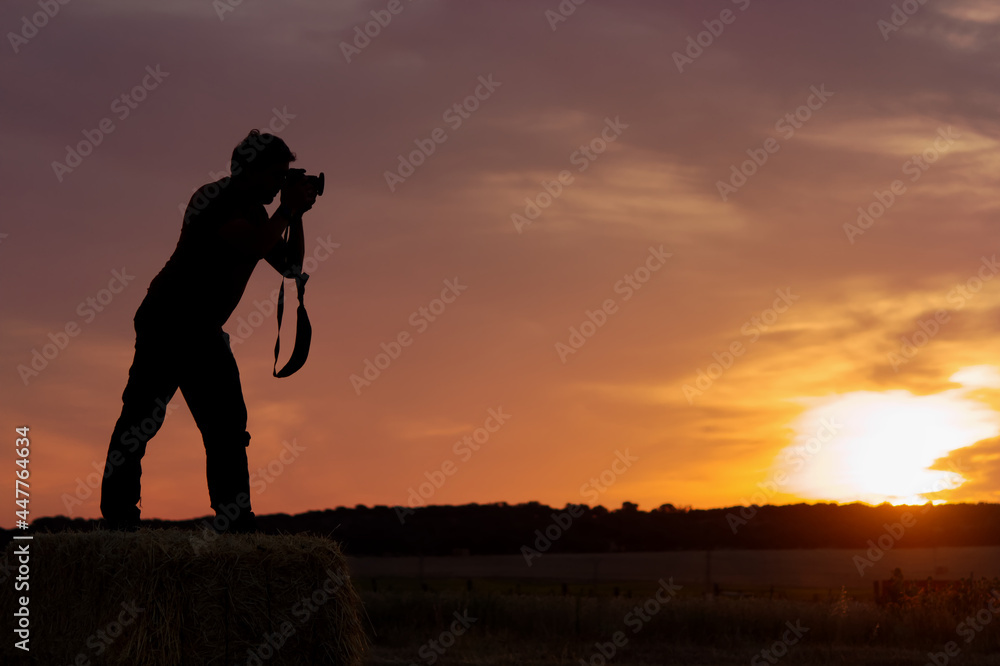 silhouette of back lit photographer taking pictures in golden hour