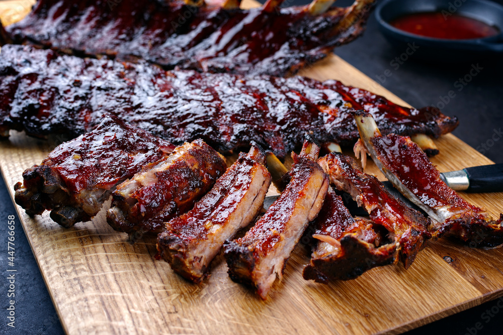Barbecue pork spare loin ribs St Louis cut with hot honey chili marinade served as close-up on a wooden board