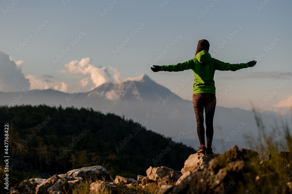rear view of woman with outstretched arms to sides against beautiful mountain landscape
