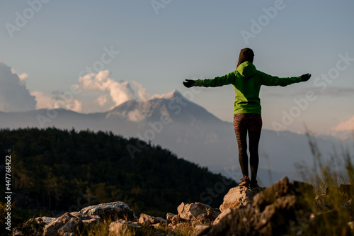 rear view of woman with outstretched arms to sides against beautiful mountain landscape